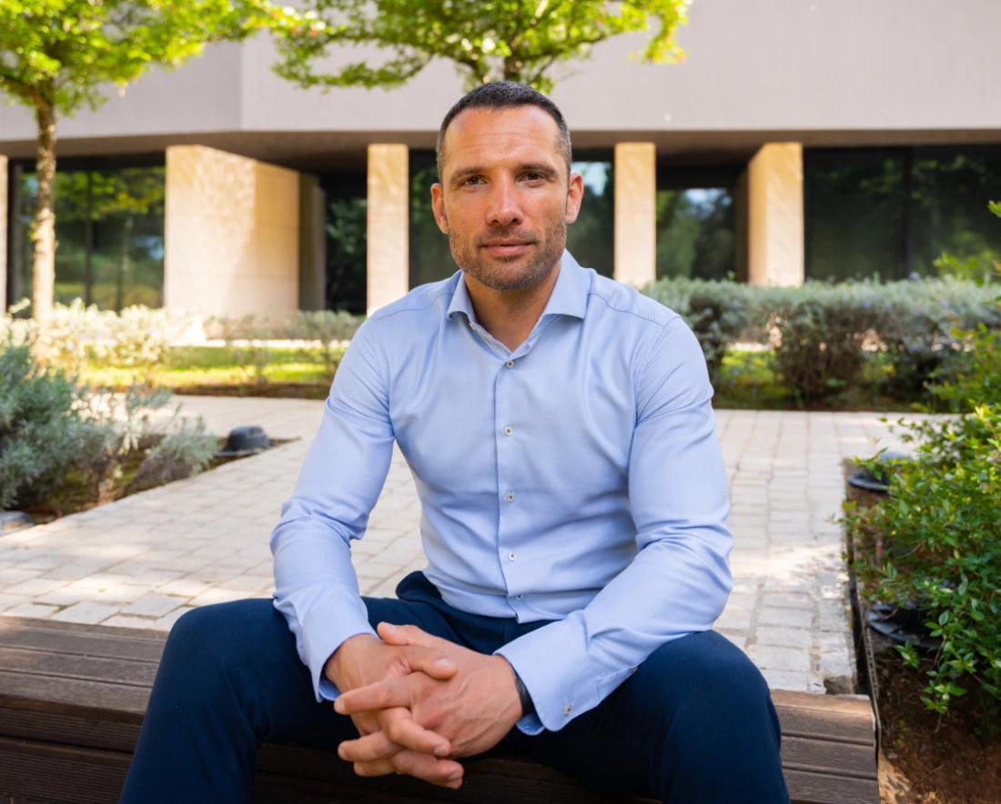 Man dressed smart, sitting on a bench, looking at the camera and smiling