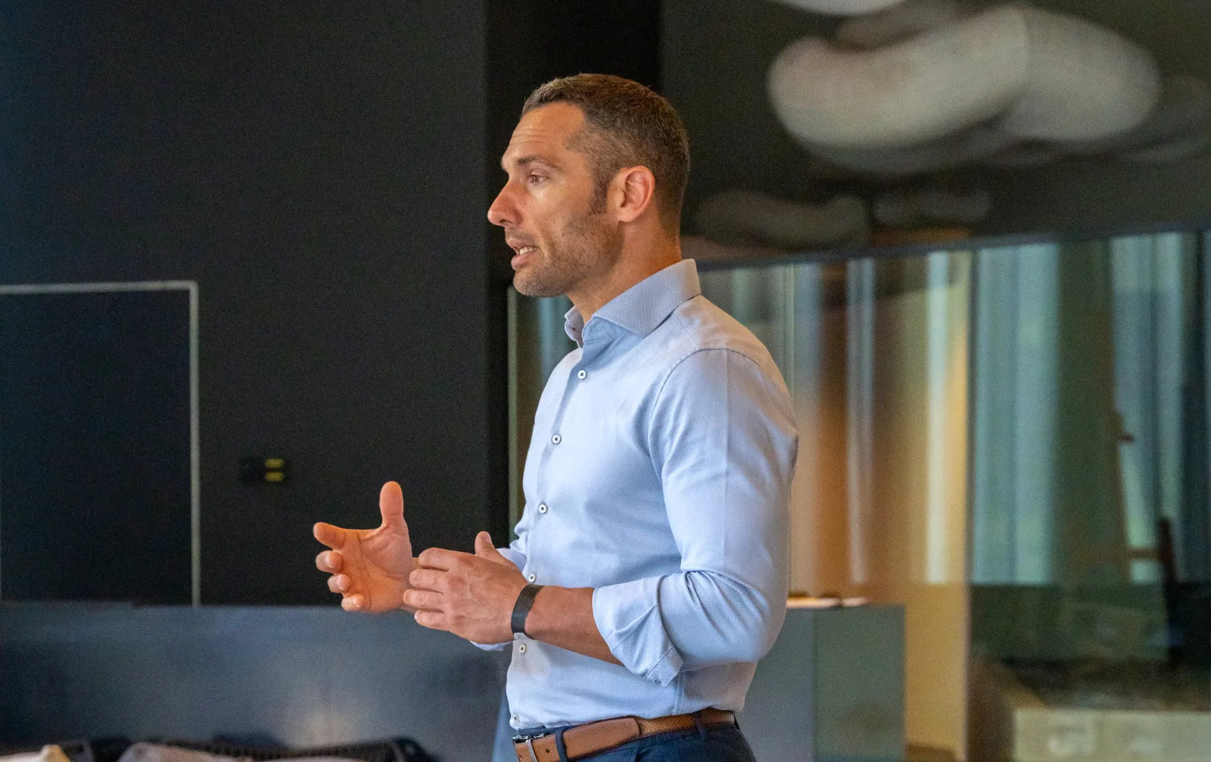 Man in a shirt standing in front of an audience and presenting